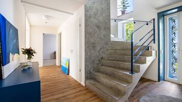 A modern interior with a staircase, wooden flooring, and a painting on the wall.