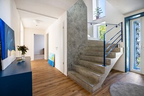 A modern interior with a staircase, wooden flooring, and a painting on the wall.