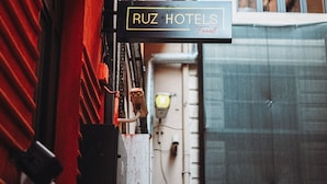 Placa de hotel com 'RUZ HOTELS' e vista para um edifício com varanda e janela.