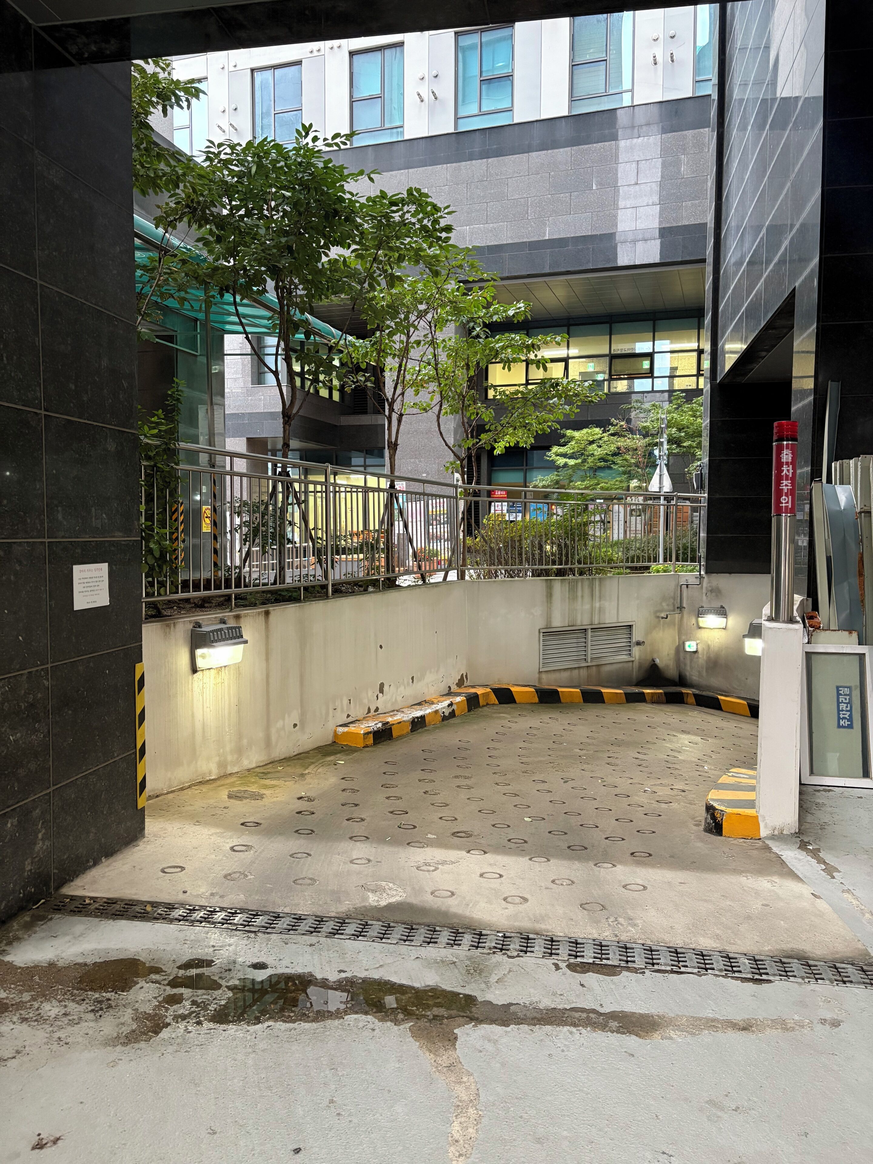 A parking area with a concrete floor, metal railings, and a tree in the background.
