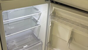 Un réfrigérateur vide, doté de plusieurs étagères et d’un compartiment congélateur.