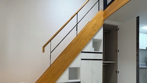 Un escalier avec des marches en bois et des rampes en métal, menant à un espace de rangement blanc doté d’armoires.