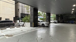 Un parking avec des planchers et des piliers en béton, une voiture blanche garée, et un bâtiment avec un toit végétalisé en arrière-plan.