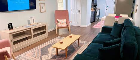 A living room with a TV, a coffee table, a sofa, a chair, and a rug.