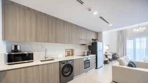 Eine moderne Küche mit Einbaugeräten, ein Essbereich mit Tisch und Stühlen sowie ein Wohnzimmer mit einer Couch.