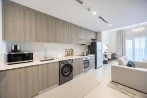 Eine moderne Küche mit Einbaugeräten, ein Essbereich mit Tisch und Stühlen sowie ein Wohnzimmer mit einer Couch.