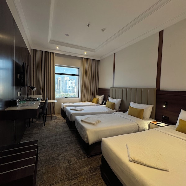 A hotel room with a desk, two beds, a TV, and a large window with a city view. - Park Plaza Hotel (Makkah)
