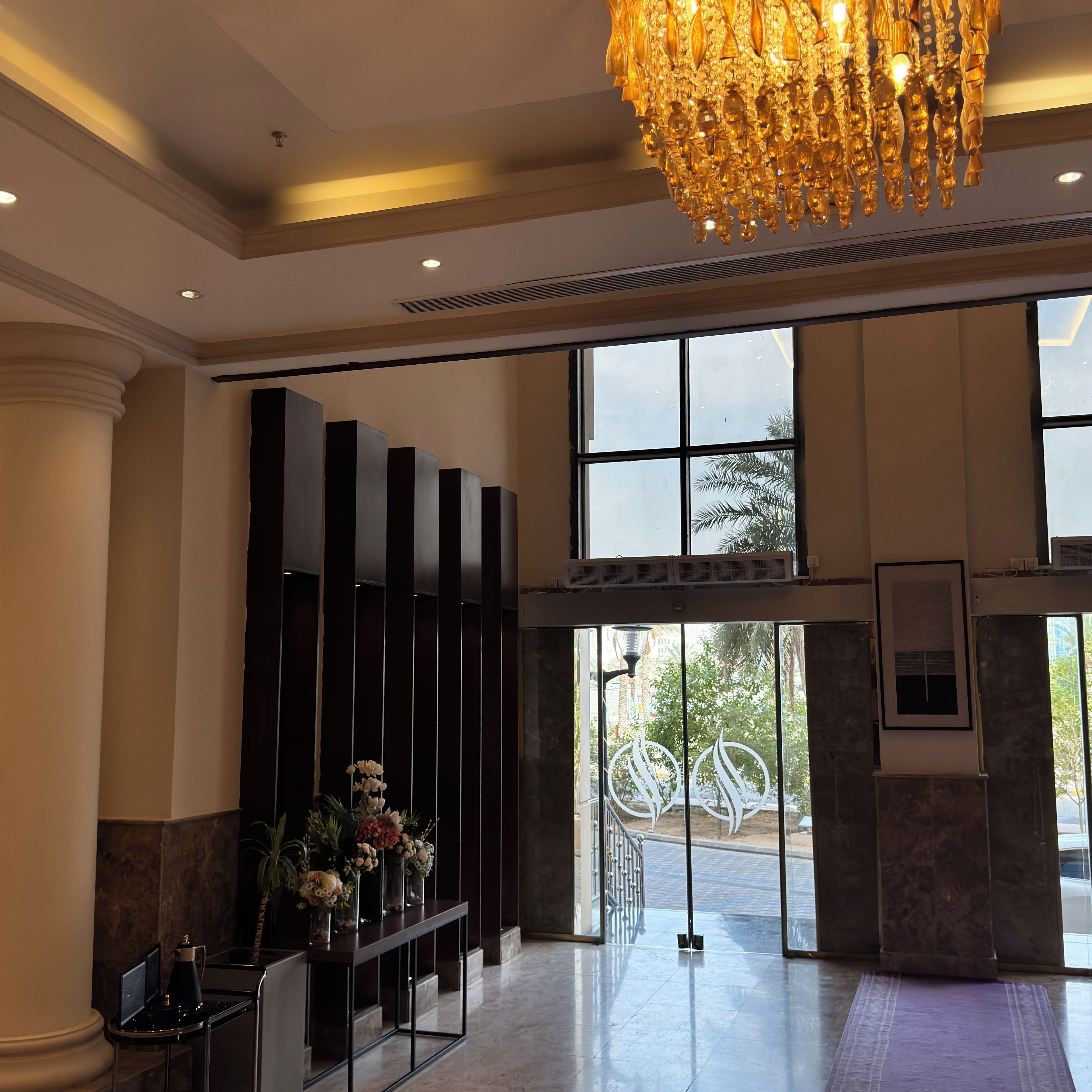 Un hall d’entrée agrémenté d’un lustre, d’un comptoir de réception et de grandes fenêtres.