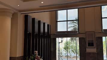 Un hall d’entrée agrémenté d’un lustre, d’un comptoir de réception et de grandes fenêtres.