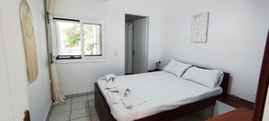 Ein Schlafzimmer mit einem Bett, einem Fenster, einer Tür und einem an der Wand befestigten Kunstwerk.