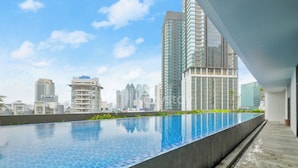 Piscina infinita en la azotea con el horizonte urbano al fondo.