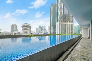 Ein Infinity-Pool auf dem Dach mit Stadtansicht im Hintergrund.