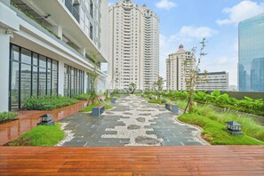 A modern urban courtyard with a wooden deck, stone pathway, and lush greenery. - Cerova by Kozystay - Sudirman (South Jakarta)