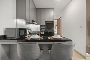 Een moderne keuken met een inbouw eiland, twee grijze stoelen en een koelkast.