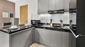 Una cocina moderna con microondas integrado, estufa y lavaplatos. Se observa una puerta de madera y una pared blanca con un interruptor de luz.