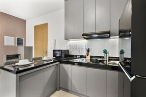 Eine moderne Küche mit integriertem Mikrowellenherd, Herd und Spüle. Eine Holztür und eine weiße Wand mit Lichtschalter sind ebenfalls vorhanden.