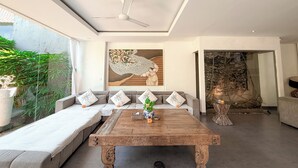 A modern living room with a sofa set, a wooden coffee table, and a ceiling fan. - Villa Alexia in Seminyak - 5 minutes walk to Beach (Seminyak)