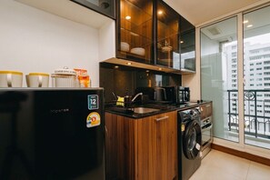 Eine moderne Küche mit einem schwarzen Kühlschrank, Holzschränken, einem eingebauten Backofen und einer Waschmaschine.