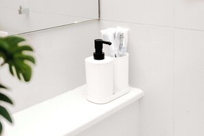 Ein Badezimmer mit einem weißen Regal, das einen Pumpspender und mehrere Röhren mit Pflegeprodukten enthält.