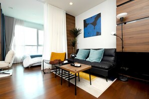 Ein modernes Wohnzimmer mit einer Couch, einem Couchtisch, einem Sessel und einem Bild an der Wand.