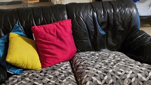 Ein Wohnzimmer mit einer schwarzen Ledersofa, einer Holztreppe und einem Bücherregal.