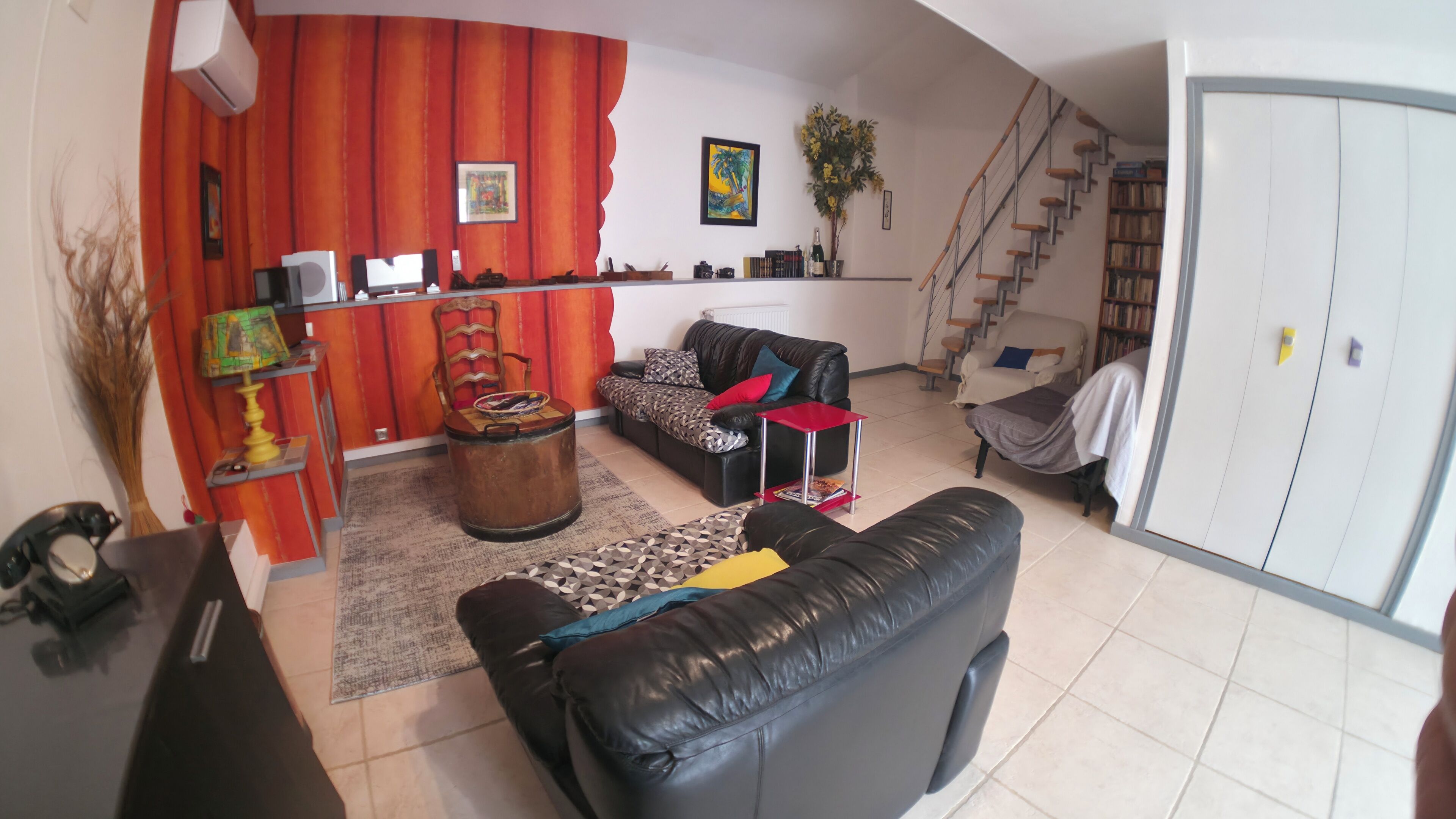 A living room with a sofa, a coffee table, a bookshelf, a staircase, and a door.
