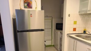 Eine kleine Küche mit einem Edelstahl-Kühlschrank, einer Mikrowelle und einem Spülbecken.
