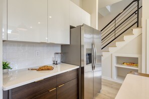 Eine moderne Küche mit einem Edelstahl-Kühlschrank, Holzschränken und einer weißen Arbeitsplatte.