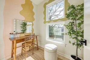 Habitación con tocador, espejo, silla y planta en maceta.