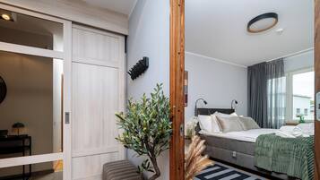 Una camera da letto moderna con un letto, lampade da comodino, uno specchio e una pianta.