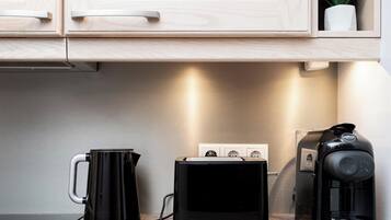 Une cuisine équipée d’une machine à café, d’un appareil électroménager noir et d’une prise de courant.