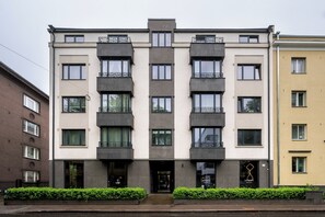 Un edificio de varios pisos con fachada simétrica, que presenta una entrada central con una puerta oscura y ventanas en cada planta.