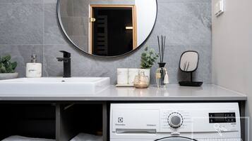 Un baño moderno con lavamanos, espejo y lavadora abajo.