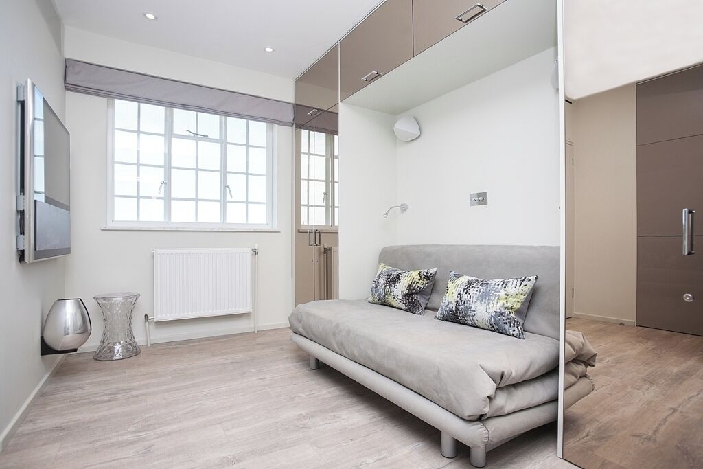 A modern room with a sofa, a radiator, a window, and a cabinet.