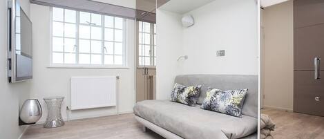 Una habitación moderna con sofá, radiador, ventana y armario.