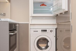 A compact laundry area with a washing machine, dryer, and a microwave. - Tranquil Small Studio with AC in vibrant Chelsea (London)