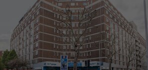 A multi-story building with a brick facade, multiple windows, and a parking sign indicating 24/7 availability. - Tranquil Small Studio with AC in vibrant Chelsea (London)