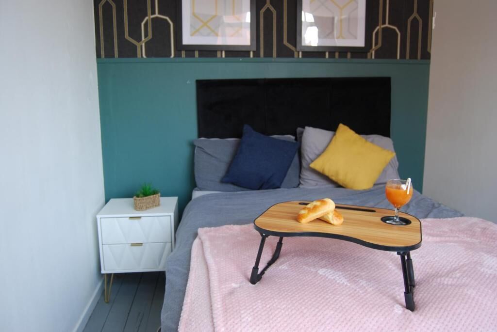 A neatly arranged bedroom with a bed, bedside table, and a tray with bread and juice.