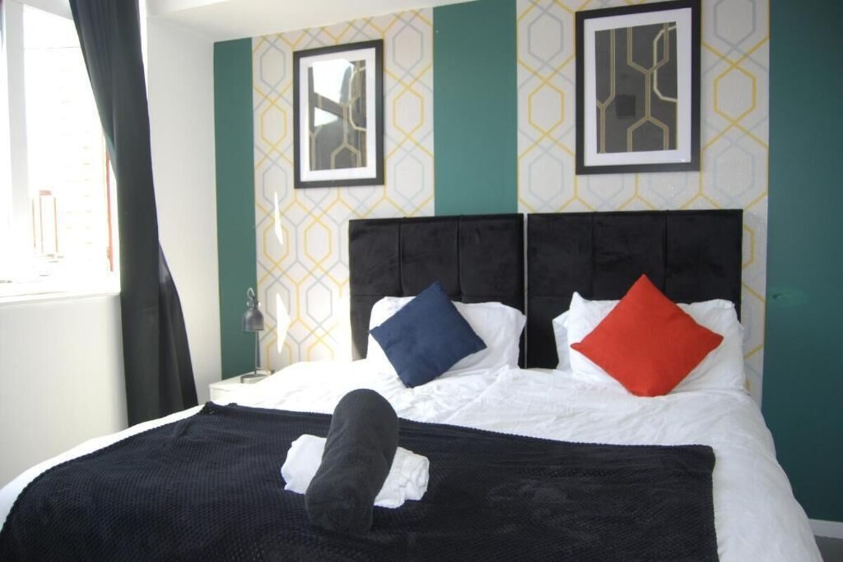 Ein Hotelzimmer mit einem Bett, zwei Kissen, einer Decke und einem Nachttisch mit einer Lampe.