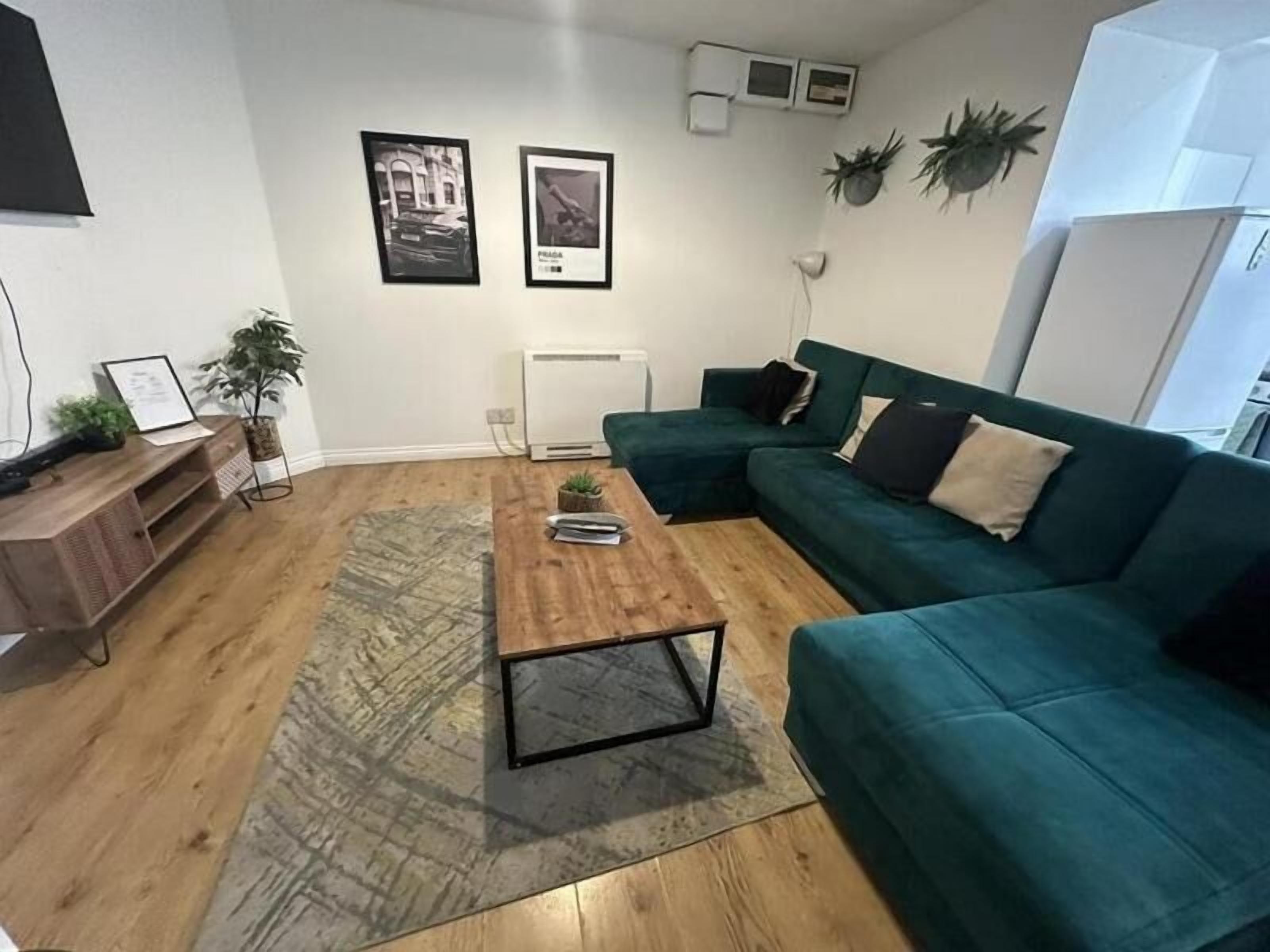 Een woonkamer met een houten salontafel, een blauwgroene bank en een radiator.