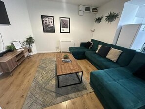 Ein Wohnzimmer mit Couch in Türkis, Holztisch und Heizkörper.