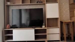 Un soggiorno moderno con una grande televisione a schermo piatto, scaffalature in legno e un design minimalista.