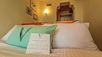 Ein Hotelzimmer mit einem Bett, einem grünen Kopfkissen, einer Willkommenskarte und einer Wandleuchte.