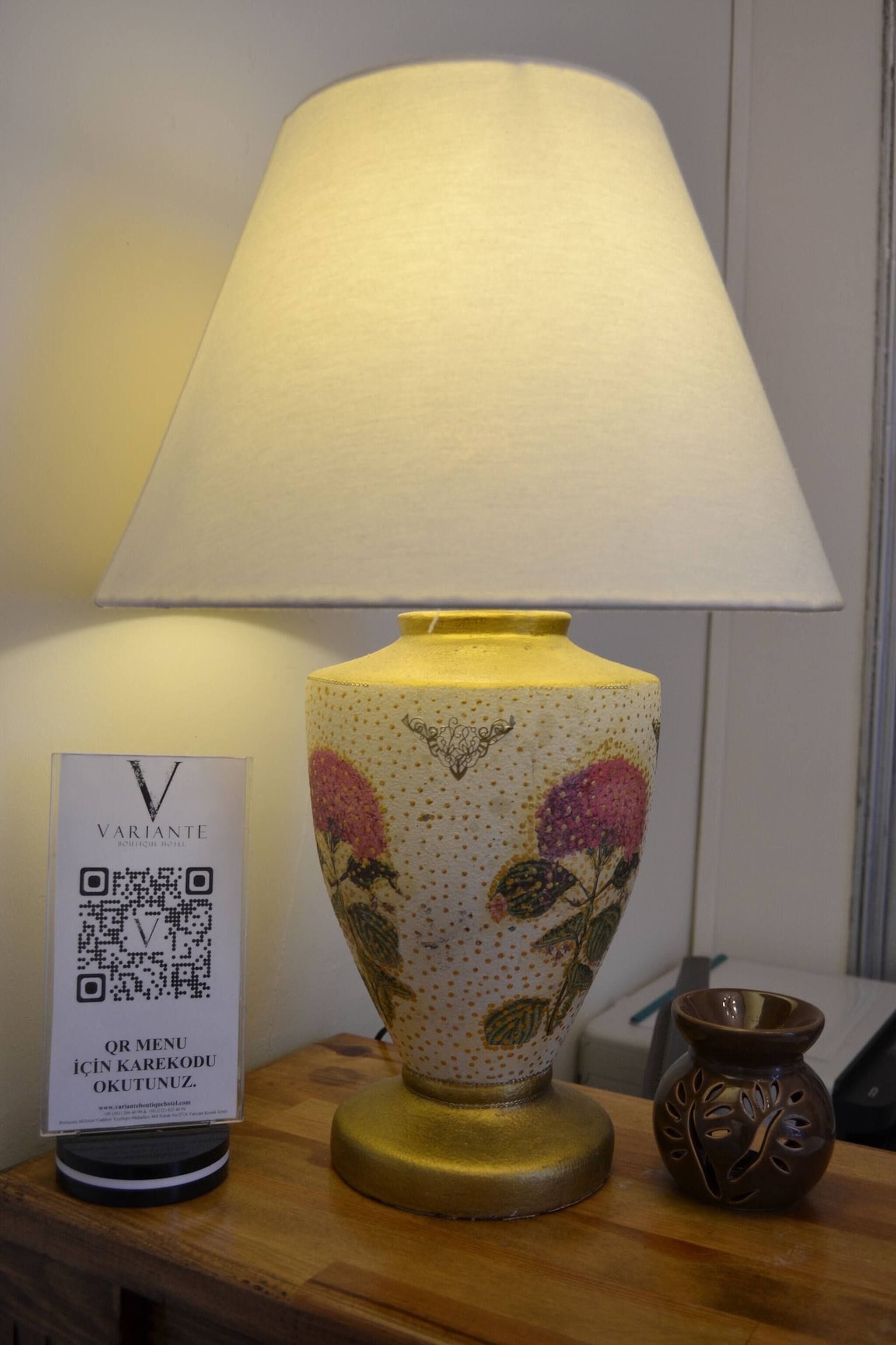 A table with a lamp, a QR code sign, and a small vase.