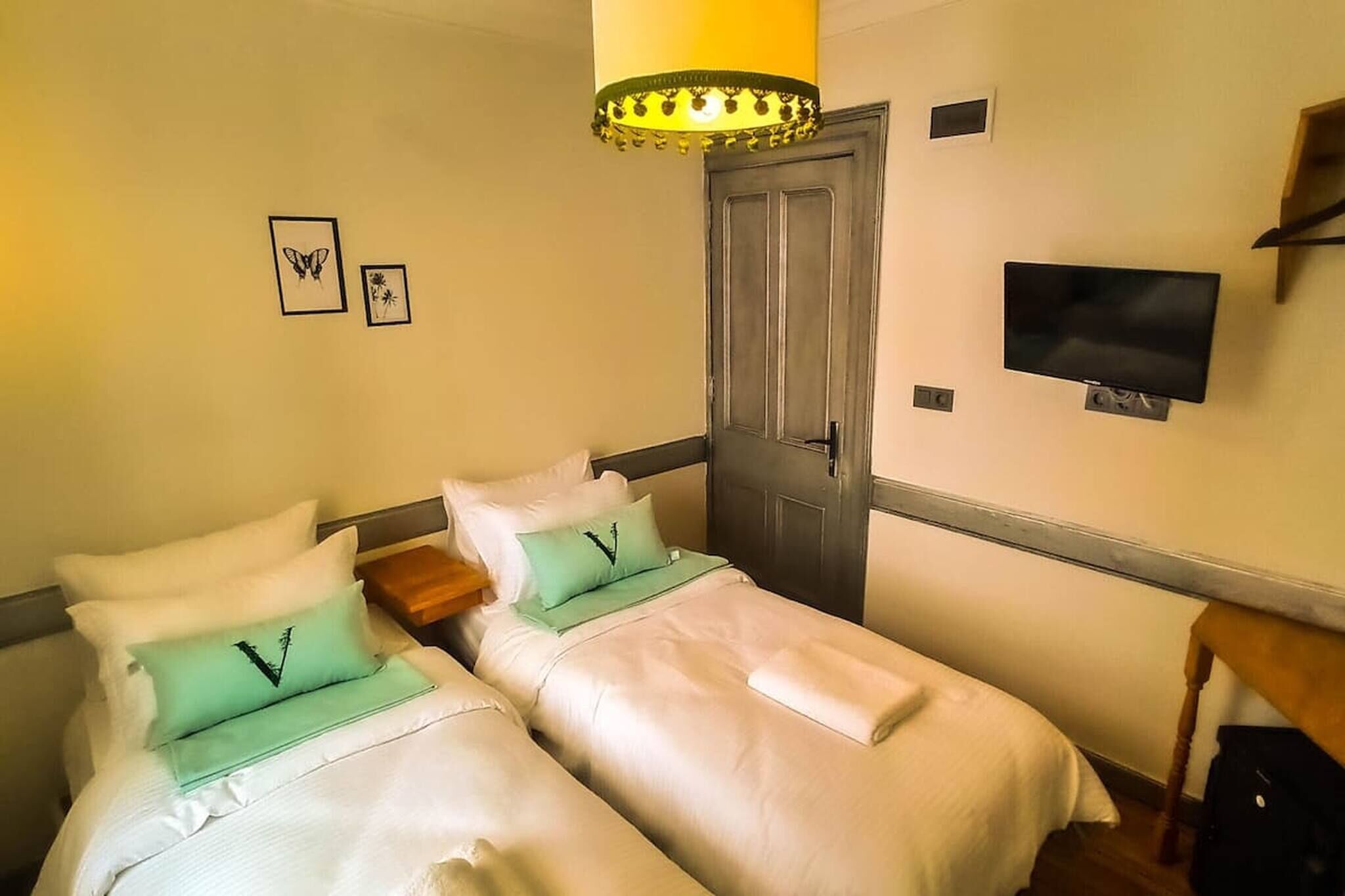 A hotel room with two beds, a television, a door, and a small table.
