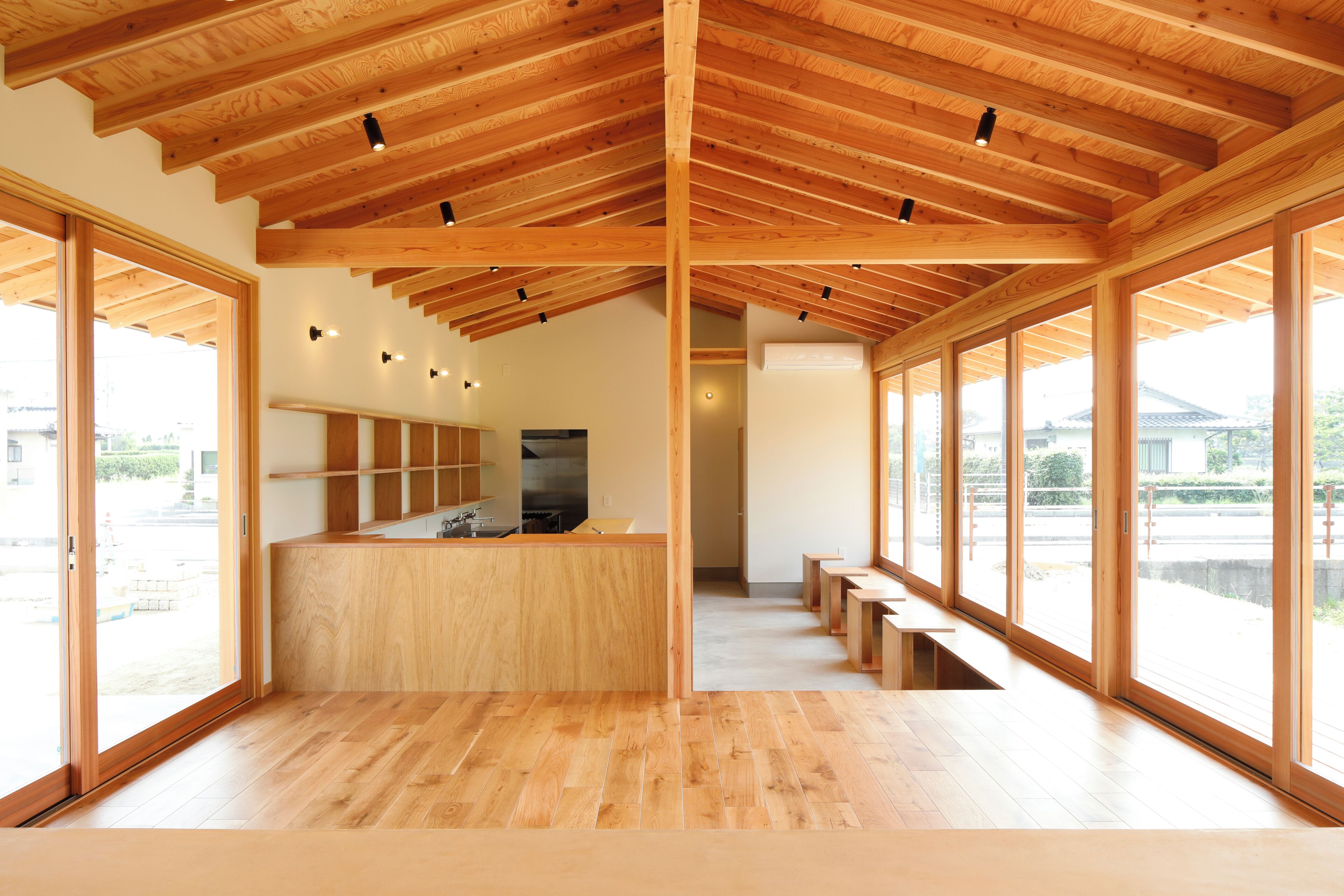 A spacious interior with wooden beams, a central kitchen area, and large windows offering views.