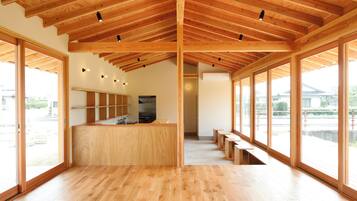 A spacious interior with wooden beams, a central kitchen area, and large windows offering views.
