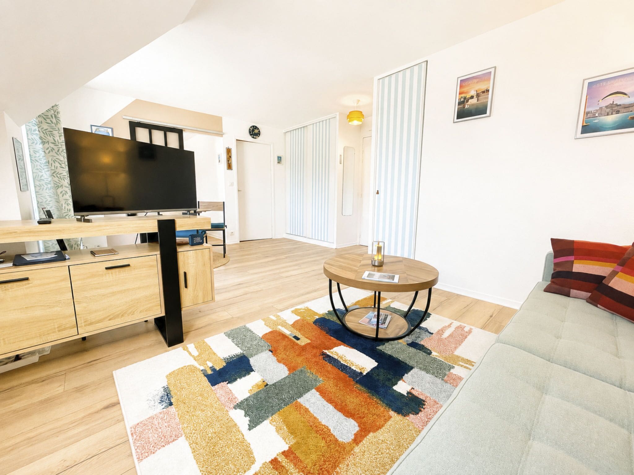 Un salon moderne avec un téléviseur à écran plat, des meubles en bois, un tapis à motifs et un canapé.