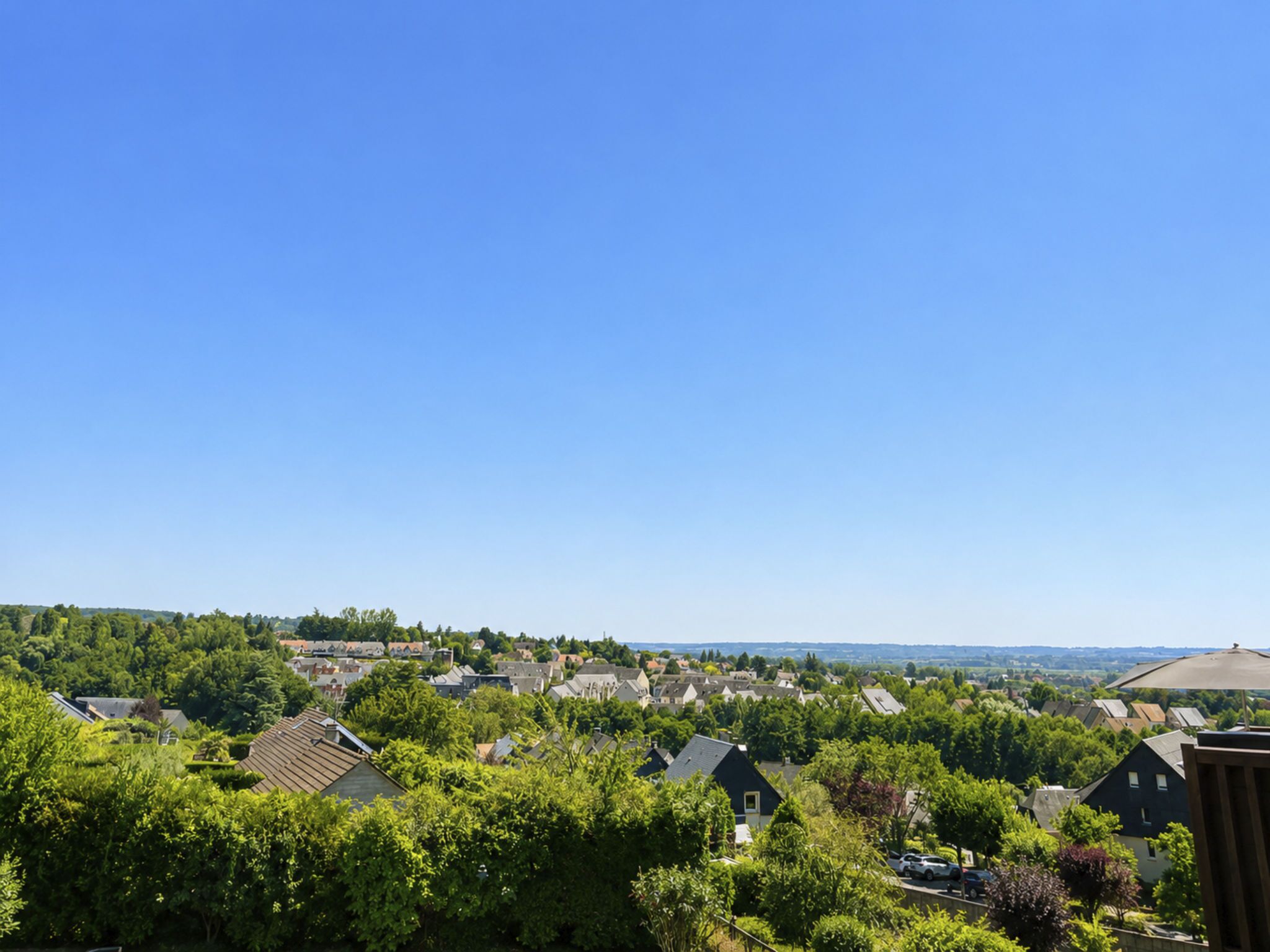 Een woonwijk met huizen, groen en een helderblauwe lucht.