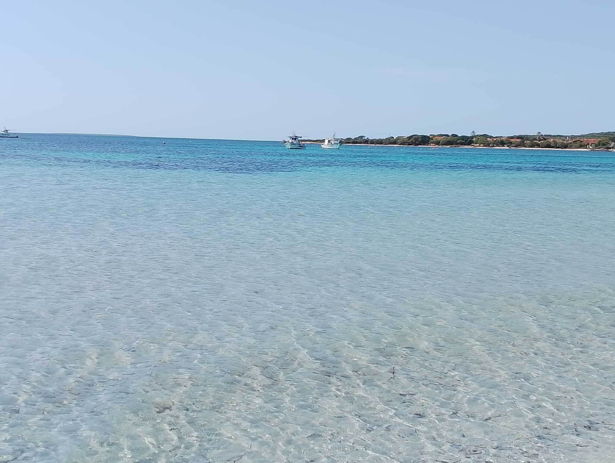 Una spiaggia con acque cristalline e barche.